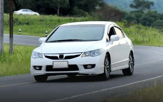 白い小型車の走行写真